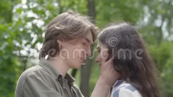 可爱的年轻夫妇亲密亲吻的肖像快乐的女孩和男孩一起在公园里度过时光休闲视频的预览图
