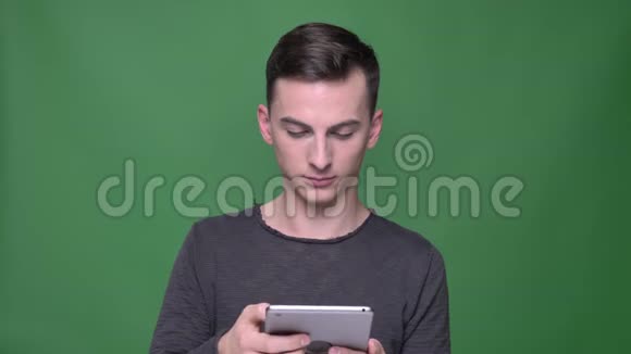 在平板电脑上拍摄年轻英俊的白种人男性短信特写镜头背景与绿色隔离视频的预览图
