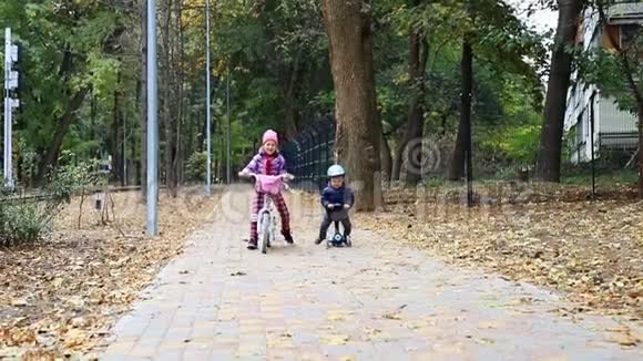 小男孩骑着滑板车骑着平衡车骑在柏油路旁妈妈在城市公园附近散步视频的预览图