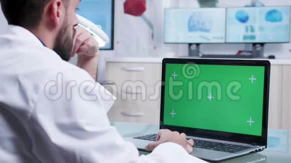 在绿色屏幕笔记本电脑上工作的医务人员肩膀上的静态镜头视频的预览图