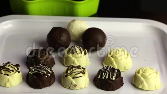 一个戴着橡胶手套的人把巧克力从一个容器上传到一个托盘上白色和黑色巧克力中的釉糖国际视频的预览图