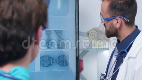 医生和护士用DNA样本近距离观察监视器视频的预览图