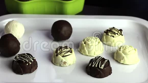一个戴橡胶手套的人把糖果放在托盘上白色和黑色巧克力中的釉糖国际糖果日视频的预览图