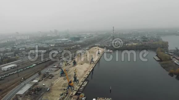 港口起重机从码头的驳船上卸下河沙挖掘机和卡车四处移动工业码头概念视频的预览图