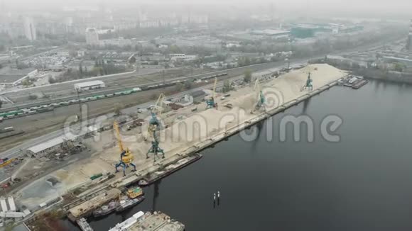 在港口工作时起重机从驳船上挑选碎石和沙子烟雾弥漫的工业城市视频的预览图