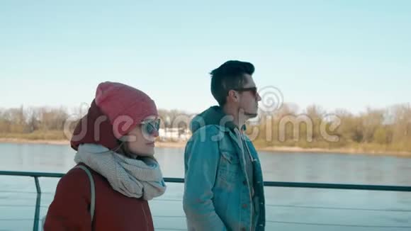 戴太阳镜的千禧一代年轻的男女朋友正在码头散步视频的预览图