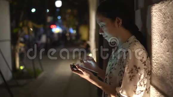 一个亚洲女人在外面的大街上用智能手机聊天视频的预览图