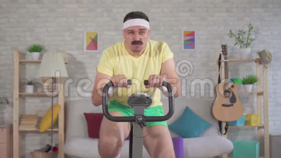 一位80的留着胡子的在家里骑着一辆运动自行车的精力充沛的视频的预览图