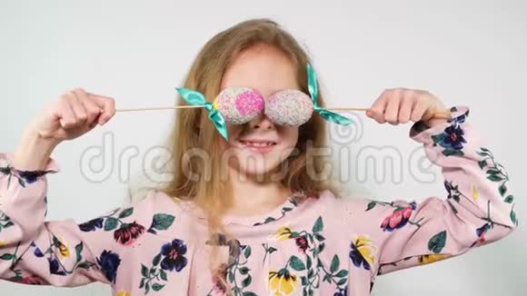 开朗的女孩玩鸡蛋睁开眼睛惊讶可爱的女孩在棍子上用复活节彩蛋跳舞视频的预览图