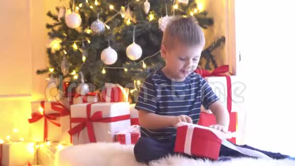 可爱的小男孩解开圣诞礼物孩子在家开新年礼物视频的预览图
