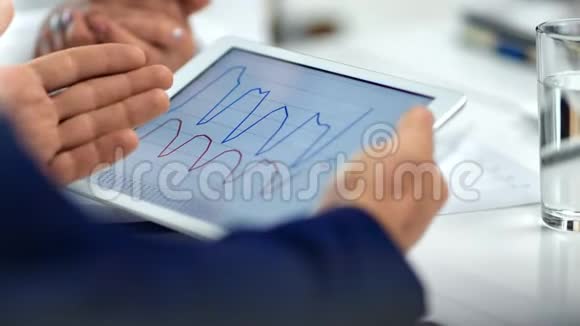 特写商人男性手持平板电脑显示数据图形讨论在团队会议视频的预览图
