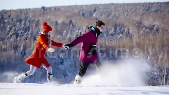 在阳光明媚的日子里幸福的一对夫妇在山地滑雪场慢动作地奔跑冬季体育假日恋爱视频的预览图