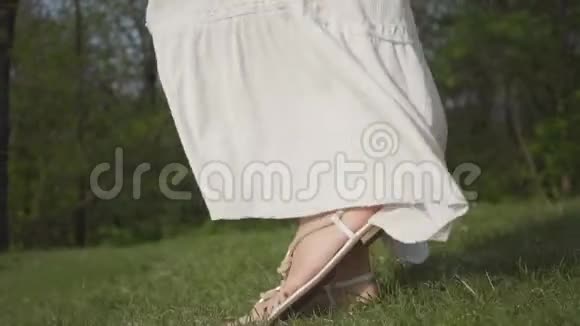 漂亮的女人穿着白色长裙和牛仔裤夹克带着手机近距离穿过森林照相机移动视频的预览图