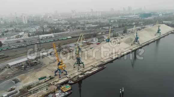 货运港口起重机在一堆沙子附近的鸟瞰船和驳船运输河沙工业城市视频的预览图
