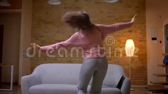 在室内舒适的公寓里年轻漂亮的黑发白种人女性在跳舞和玩乐视频的预览图