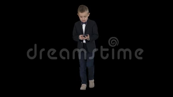 穿着服装走路和使用智能手机的小男孩阿尔法频道视频的预览图