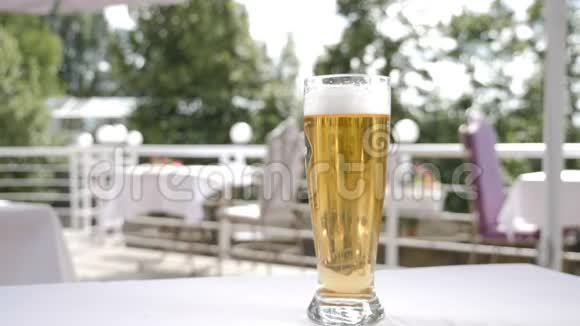 啤酒飞溅提供啤酒饮料带有深色酒精液体的小花絮落入啤酒杯中慢动作视频的预览图