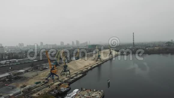 工业城市在烟雾和雾中的鸟瞰建筑起重机在码头工作运沙的砂驳船和卡车视频的预览图