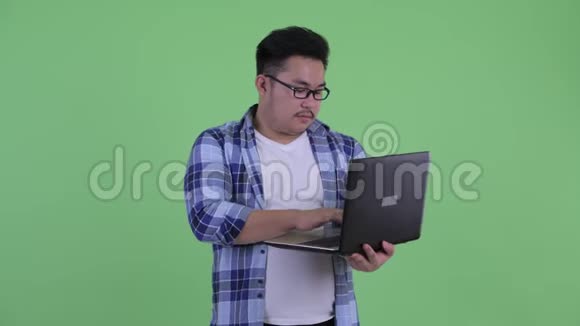 快乐年轻体重超重的亚洲时髦男人在用笔记本电脑思考问题视频的预览图
