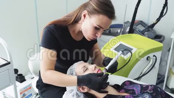 美容师在美容院做水上剥离手术将医疗器械沿着女性面部移动视频的预览图