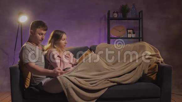 一个年轻的女人和一个男人坐在沙发上看书一男一女快乐视频的预览图