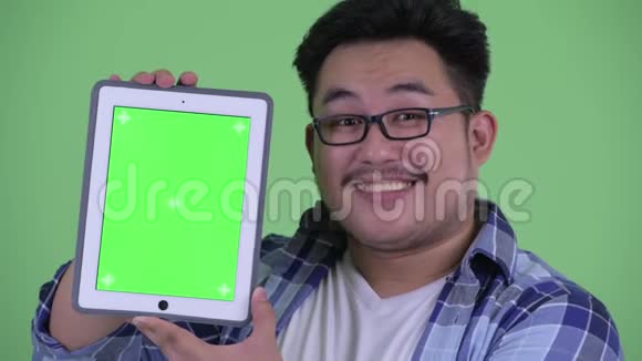 快乐年轻体重超重的亚洲时髦男人展示数码平板电脑视频的预览图