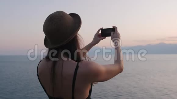 女人在日落时分用手机自拍微笑着享受大自然视频的预览图