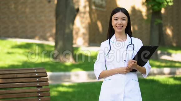 穿制服的护士站在医院公园对着镜头微笑医疗服务视频的预览图