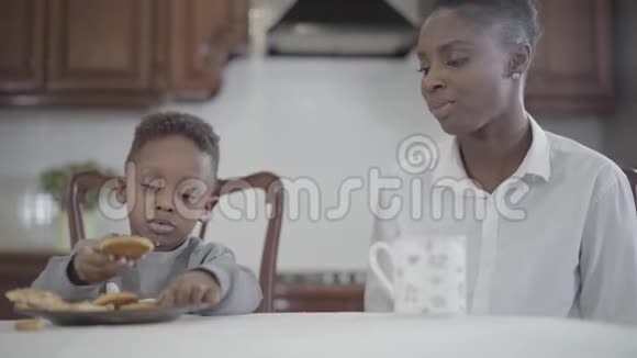 非裔美国妇女和她的小儿子坐在厨房的桌子旁夫妻关系一个幸福的家庭视频的预览图