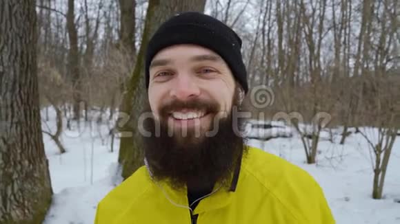 冬天森林里蓝眼睛笑着的留胡子男人的特写照片视频的预览图