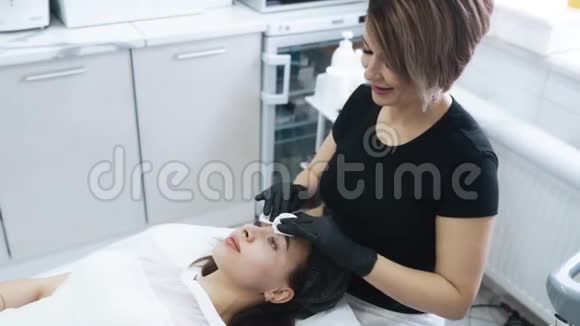 美容师在治疗前用棉垫清洁女性面部动作缓慢视频的预览图