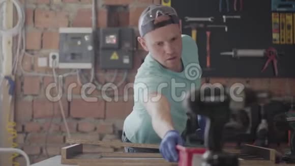 在他的木工车间里熟练的木匠用圆锯和其他机械切割一块木头视频的预览图
