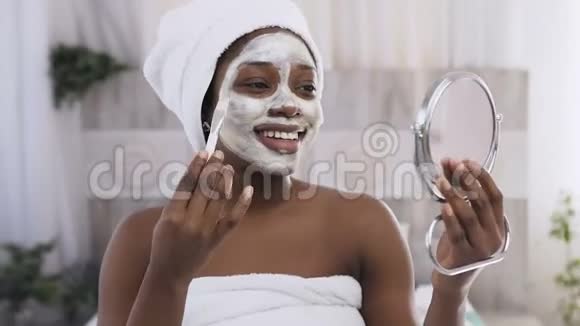 美国黑人英俊女子的肖像头上有毛巾半边脸上涂着黏土面具化妆视频的预览图