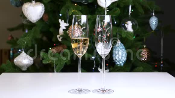 在圣诞树的背景下将香槟酒倒入酒杯中视频的预览图