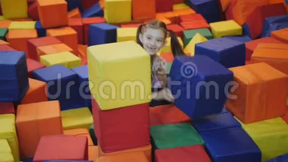 蹦床中心的小女孩建造了一座五颜六色的软立方体塔视频的预览图