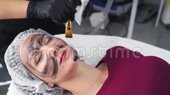 贴身美容师将黑碳面膜敷于女性面部肌肤视频的预览图