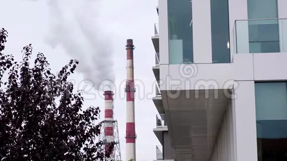 在阴沉的日子里供热站的两根管道在现代城市建筑中释放出白色的蒸汽视频的预览图