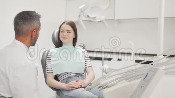 可爱的年轻女子在诊所和牙医谈话视频的预览图