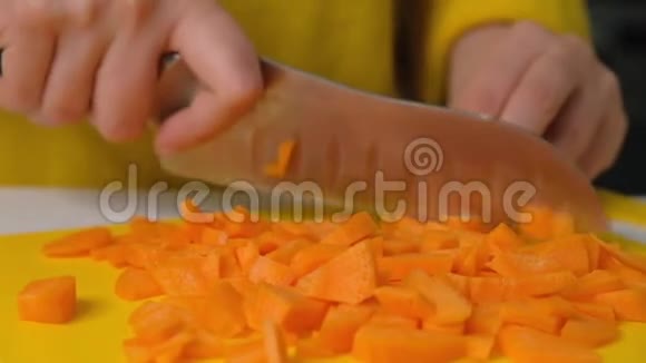女人在桌子上切胡萝卜特写把胡萝卜切到切割板上少妇在切菜视频的预览图
