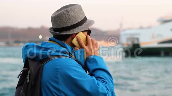戴帽子的年轻人在海边打电话视频的预览图