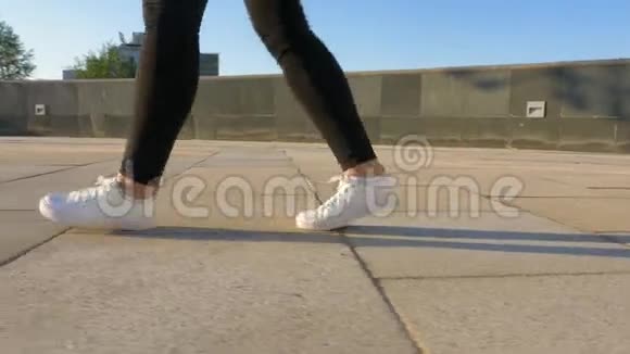 穿着白色鞋子女人的腿正沿着一条干净空荡荡的人行道走着视频的预览图