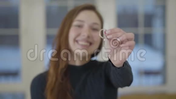 一个快乐可爱微笑的女人的肖像向相机展示一所新房子或公寓的钥匙重点视频的预览图