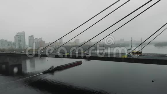 工业大都市雾中大混凝土桥和旧驳船漂浮在宽阔的河流上在国防部桥下航行的主要黄貂鱼视频的预览图