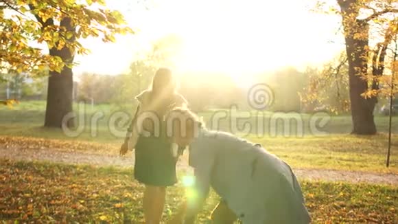 母女俩在空中抛秋叶一个女人和一个女孩在秋天的公园里玩得很开心视频的预览图
