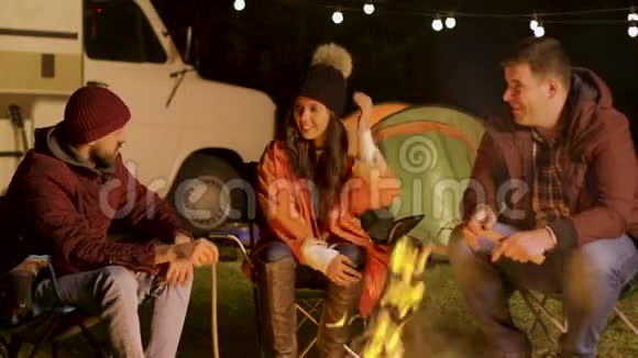 一群亲密的朋友在秋天寒冷的夜晚一起在篝火旁放松视频的预览图
