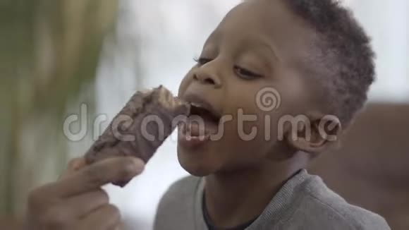 非裔美国人妈妈和可爱的儿子玩给他一块巧克力蛋糕关系妈妈和视频的预览图