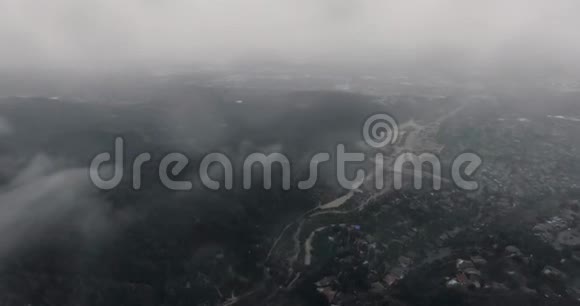 空中拍摄的城市和道路在黑色的森林在山上的云下视频的预览图