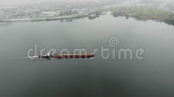 满载沙子的大型旧铁驳船正在烟雾中沿着工业市中心的河流航行煤在工业上漂浮在雾中视频的预览图
