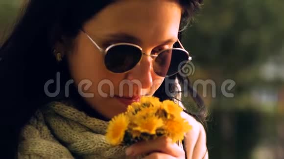 女孩在日落时嗅着花黄色的蒲公英视频的预览图