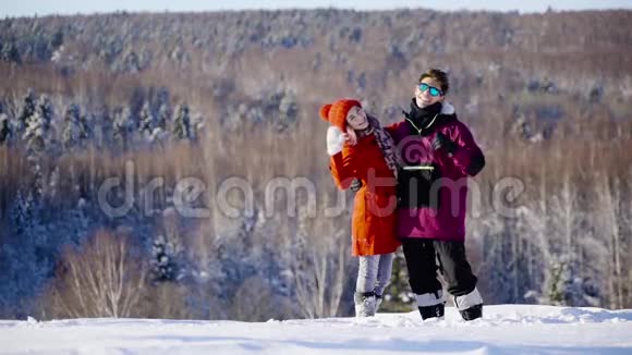 在阳光明媚的日子里快乐的年轻库普尔挥舞着双手对着山上滑雪场的镜头冬季体育假日关系视频的预览图